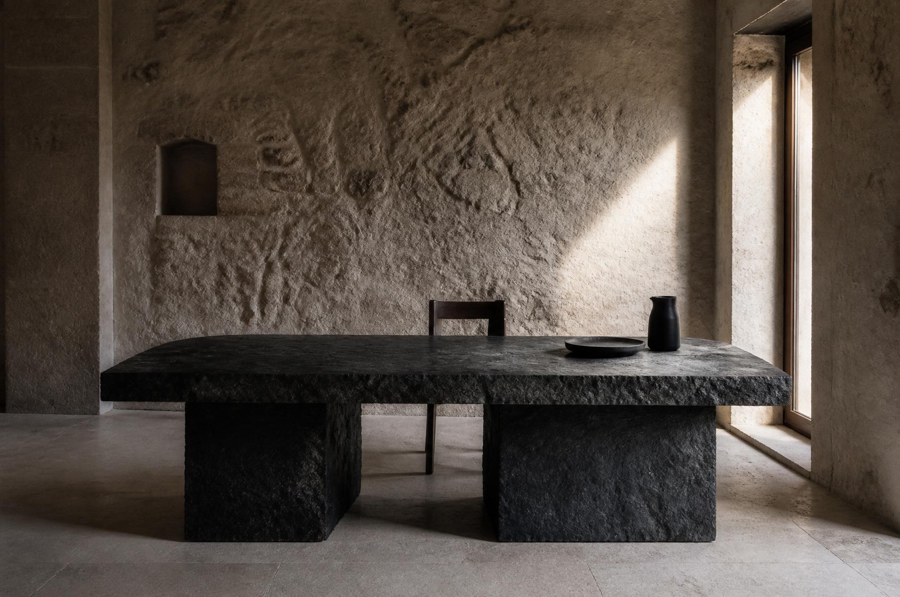 A monolithic lava stone table in a stone-walled interior