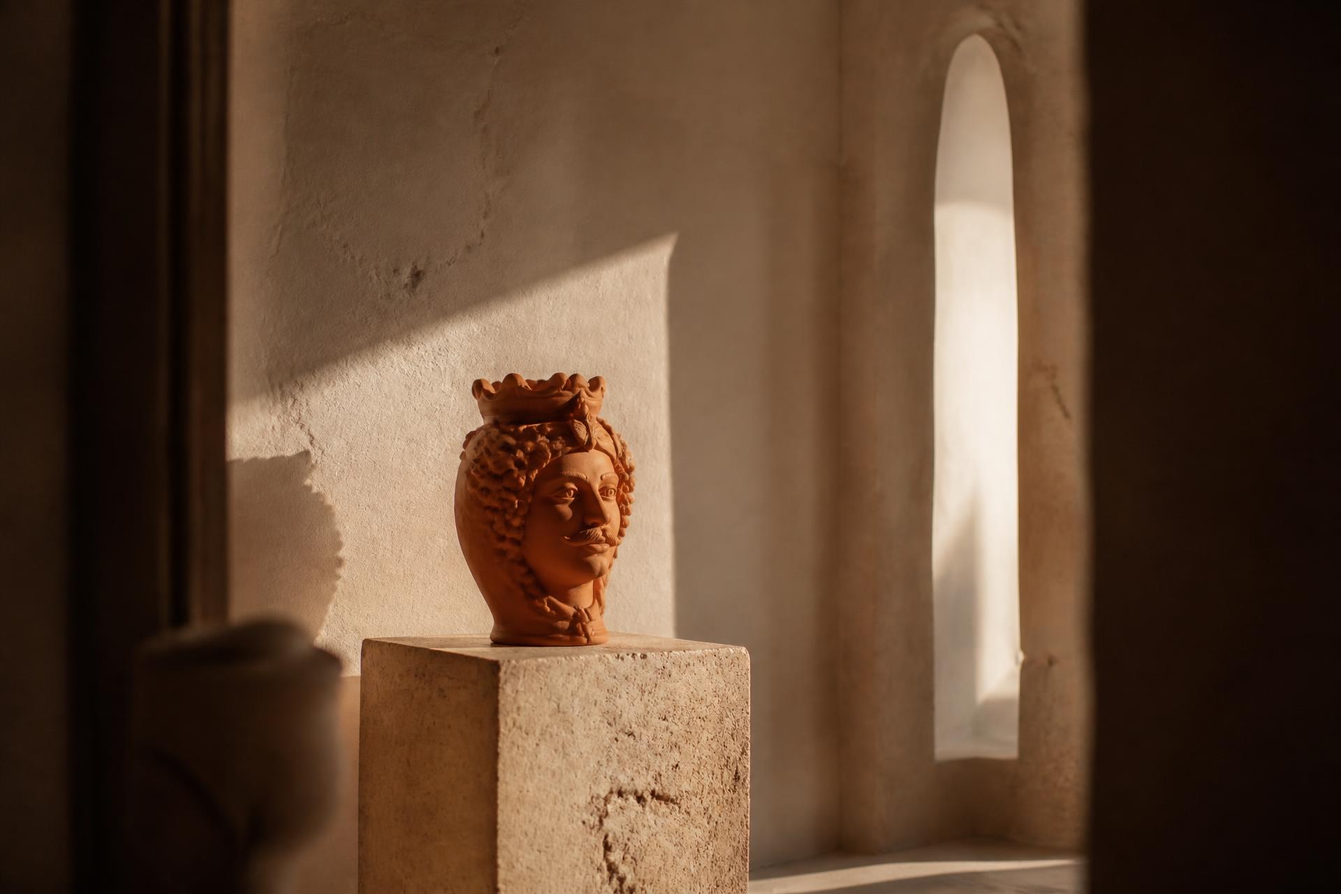 A sculptural Italian ceramic vessel on a travertine plinth in Mediterranean afternoon light